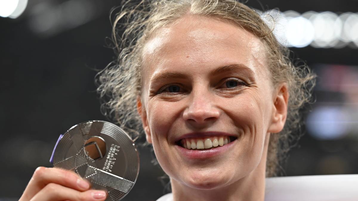 Portret Marii Żodzik, młodej kobiety z blond włosami, która uśmiecha się szeroko, trzymając w dłoni srebrny medal.