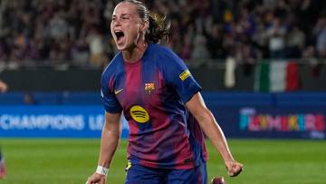 Piłkarka FC Barcelony w niebiesko-bordowym stroju radośnie biegnie po murawie, krzycząc z ekscytacji.