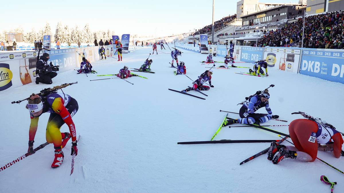Zawodnicy biathlonu na trasie biegu, niekt&oacute;rzy leżą na śniegu, inni się ścigają.