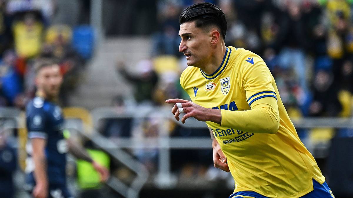 Piłkarz w żółtej koszulce z numerem 10 na plecach biegnie po boisku, wskazując palcem w prawo.