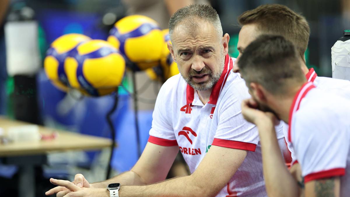 Trener siatkarskiej reprezentacji Polski, Nikola Grbić, siedzi i rozmawia z dwoma zawodnikami.