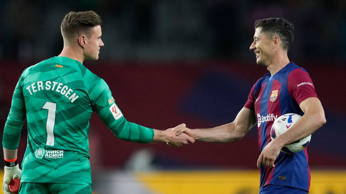 Dwóch piłkarzy ściska sobie dłonie na boisku piłkarskim. Po lewej bramkarz w zielonym stroju z numerem 1 i nazwiskiem TER STEGEN, po prawej zawodnik w koszulce Barcelony trzymający piłkę.