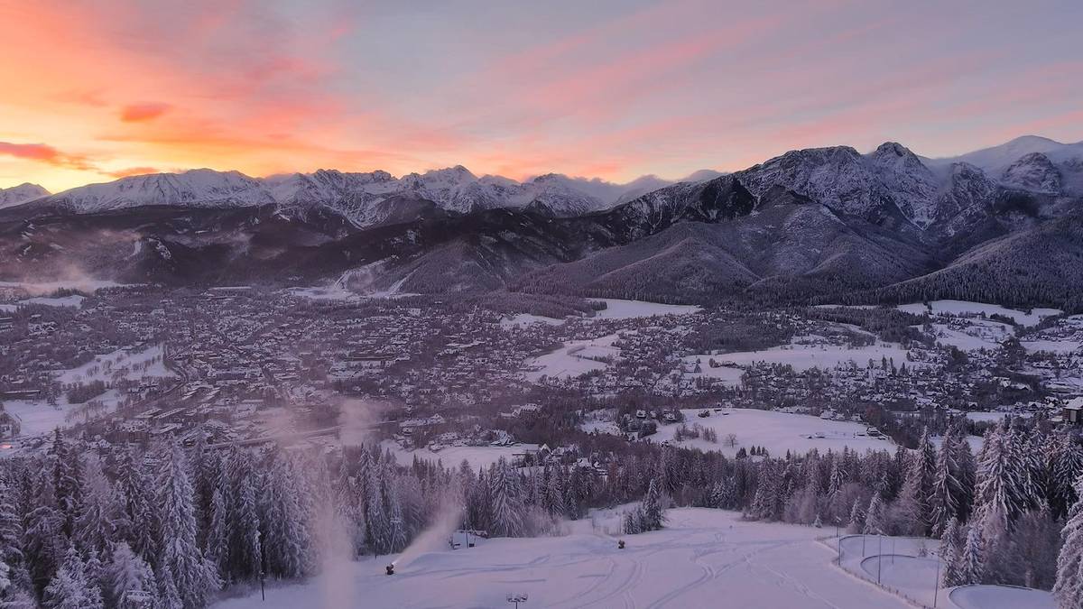 Panoramiczny widok na ośnieżone Zakopane i Tatry podczas zachodu słońca.