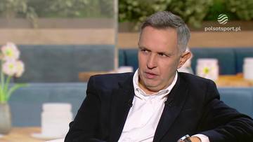 Mężczyzna w garniturze siedzi w studio telewizyjnym, m&oacute;wiąc.