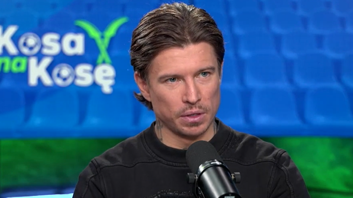 Portret Jakuba Koseckiego w studiu telewizyjnym, mówiącego do mikrofonu.