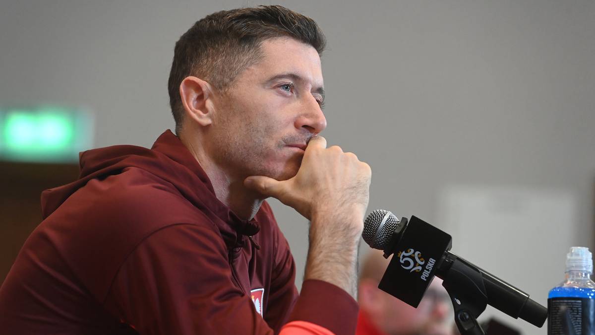 Robert Lewandowski siedzi przy mikrofonie, zamyślony.