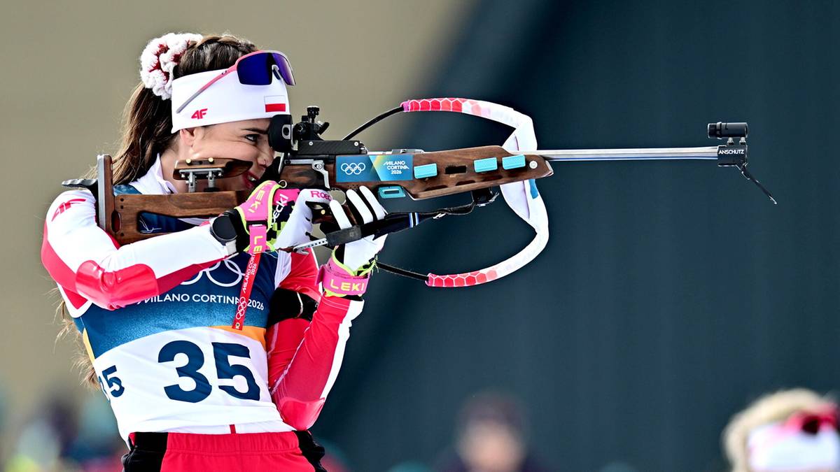 Biathlonistka w białej czapce i goglach celuje z karabinu podczas zawod&oacute;w, ma na sobie str&oacute;j z numerem 35.