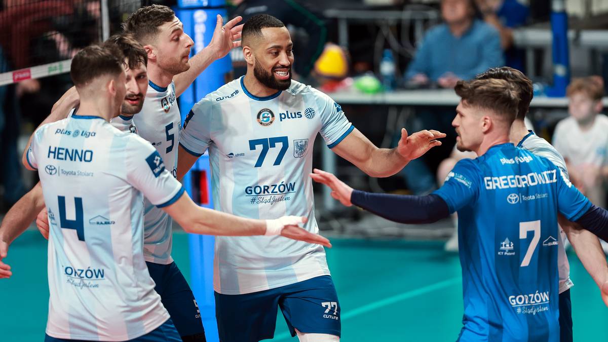 Siatkarze w białych i niebieskich strojach świętują udaną akcję na boisku.