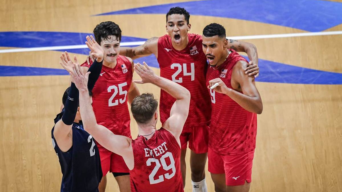 Pięciu siatkarzy w czerwonych koszulkach świętuje zwycięstwo, obejmując się i klaszcząc. Jeden z zawodników podnosi ręce w górę.