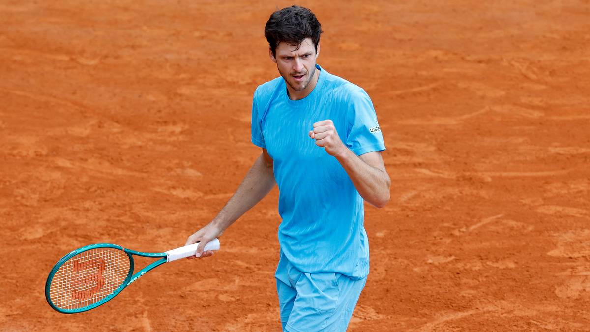 Tenisista Hubert Hurkacz świętuje zwycięstwo na korcie ziemnym, trzymając rakietę.