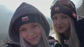 Dwie młode kobiety w zimowych czapkach z polskimi flagami, uśmiechające się do zdjęcia.