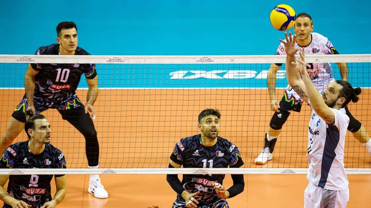 Gracze siatk&oacute;wki w akcji podczas meczu, z jednym zawodnikiem serwującym piłkę.