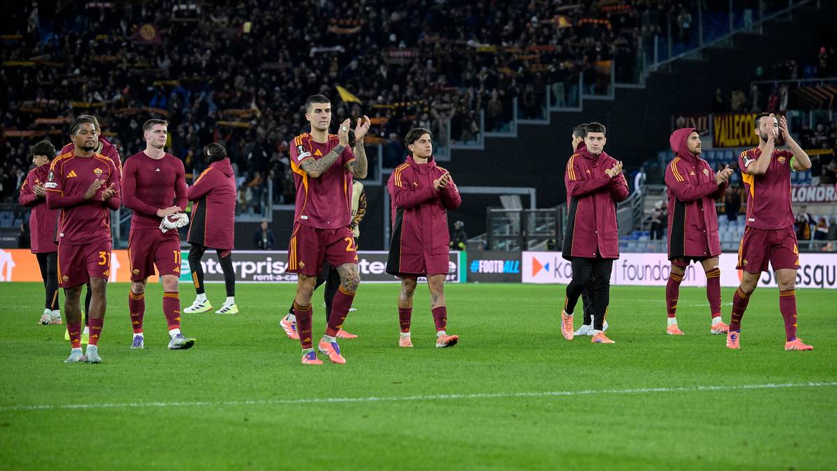 Piłkarze w czerwonych strojach wychodzą na zieloną murawę stadionu, na tle trybun wypełnionych widzami.