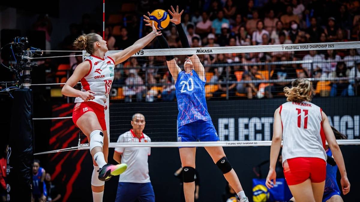 Siatkarka w białej koszulce z numerem 19 wykonuje atak nad siatką. Siatkarka w niebieskiej koszulce z numerem 20 próbuje zablokować atak.