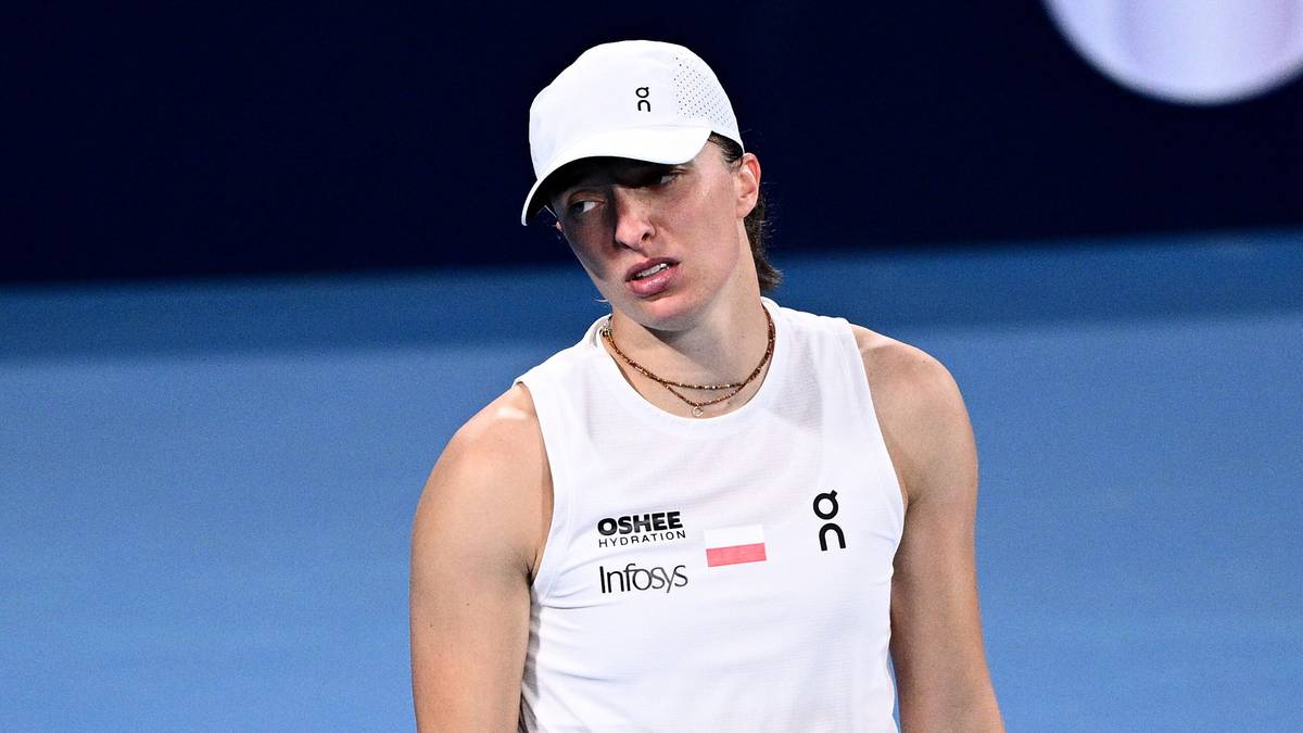 Iga Świątek w stroju sportowym stoi na korcie tenisowym z rakietą w dłoni.