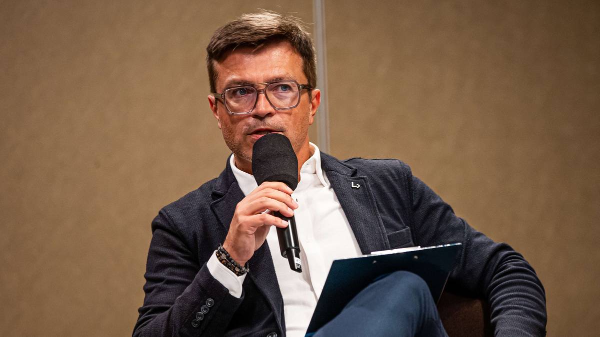 Mężczyzna w okularach z mikrofonem i notatnikiem.