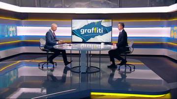 Dwóch mężczyzn w garniturach siedzi naprzeciwko siebie w studiu telewizyjnym. Na ekranie za nimi wyświetlany jest napis "graffiti".