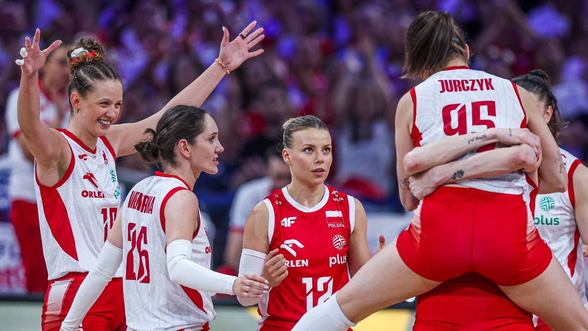 Siatkarki reprezentacji Polski w białych strojach z czerwonymi elementami radośnie świętują zdobycie punktu, otaczając jedną z zawodniczek.
