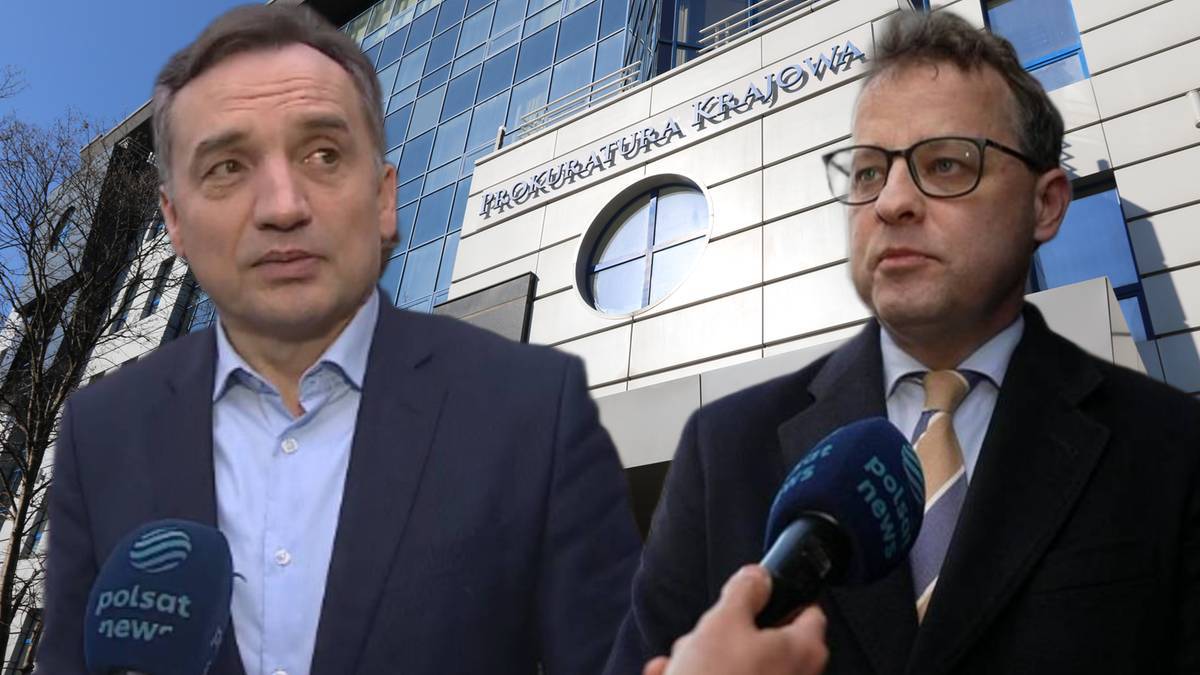 Dwaj mężczyźni w garniturach stoją przed budynkiem Prokuratury Krajowej, jeden z nich udziela wywiadu.