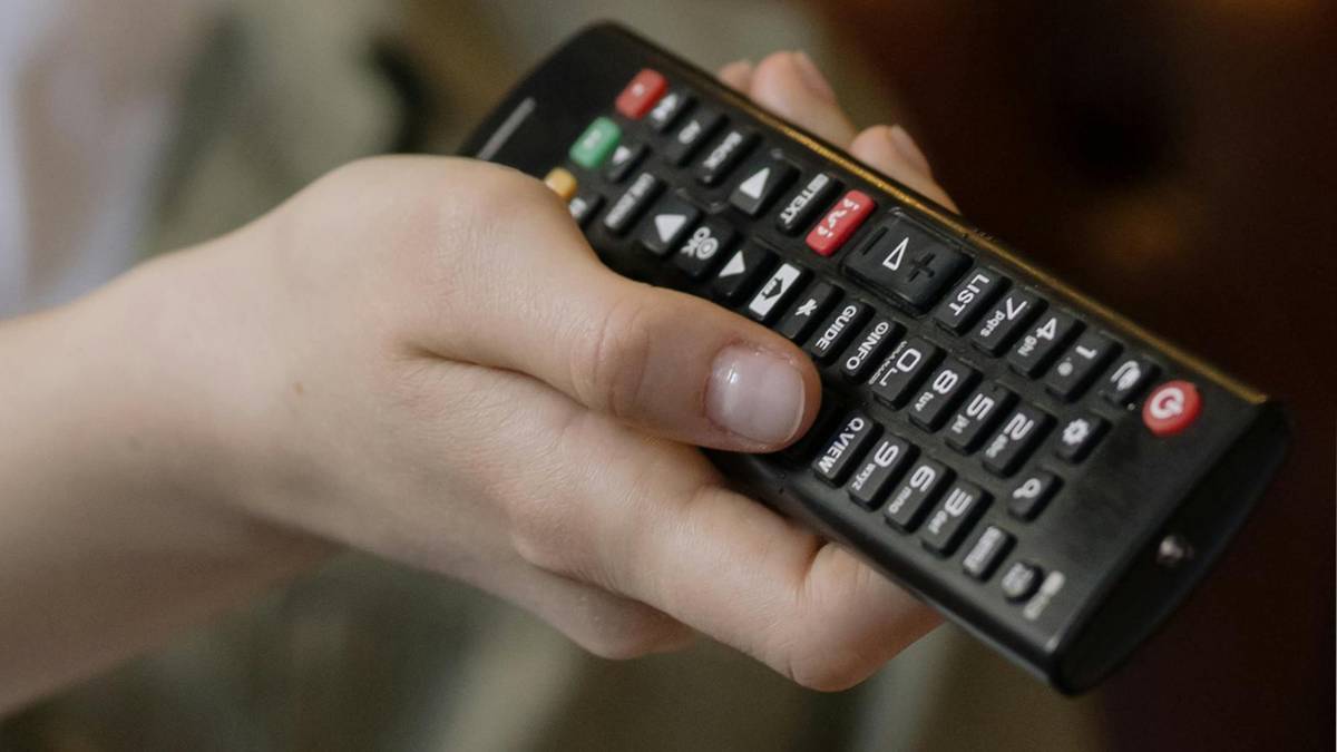 Dłoń trzymająca pilot do telewizora.