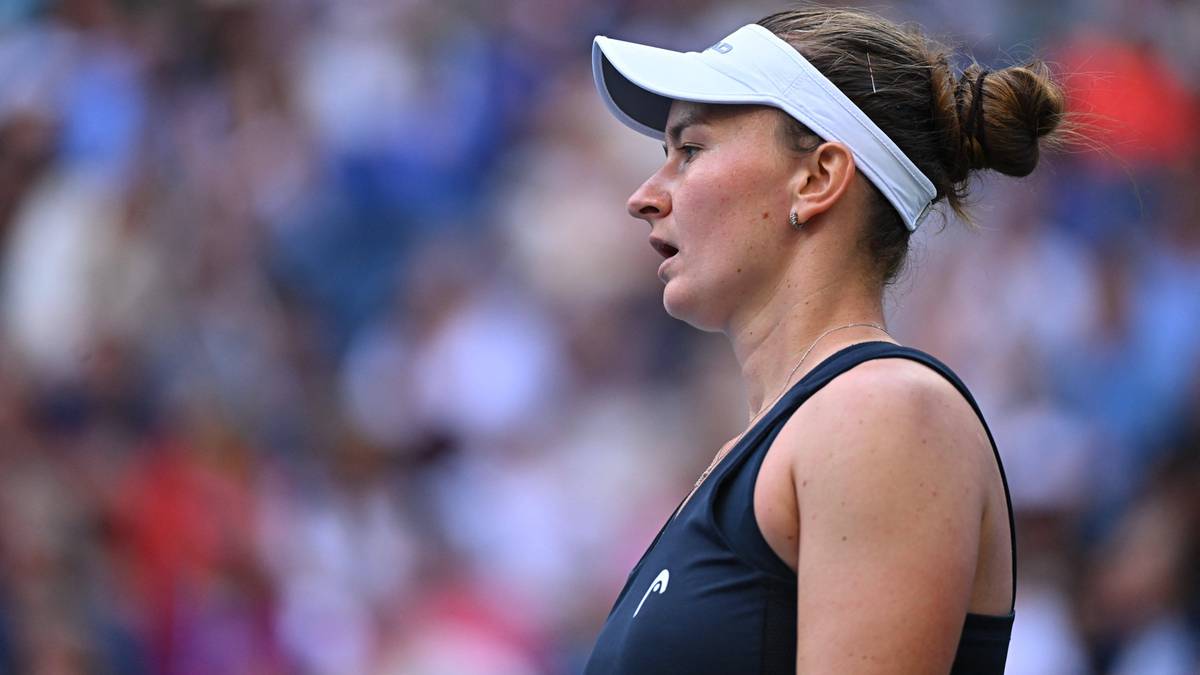 Portret kobiety w stroju tenisowym, widzianej z profilu, z zaczerwienioną twarzą, prawdopodobnie w trakcie meczu na korcie.