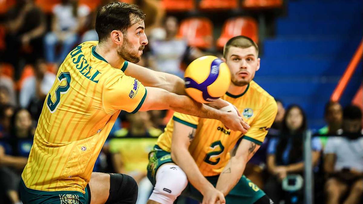 Dw&oacute;ch siatkarzy w ż&oacute;łtych koszulkach, jeden podaje piłkę drugiemu.