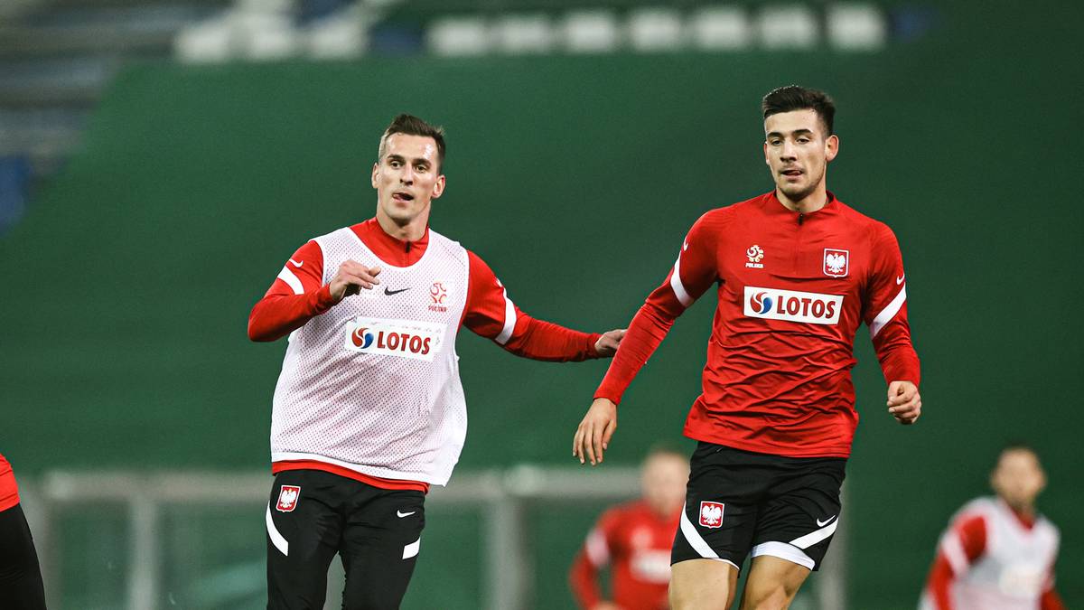 Piłkarze reprezentacji Polski w czerwonych strojach treningowych na boisku.