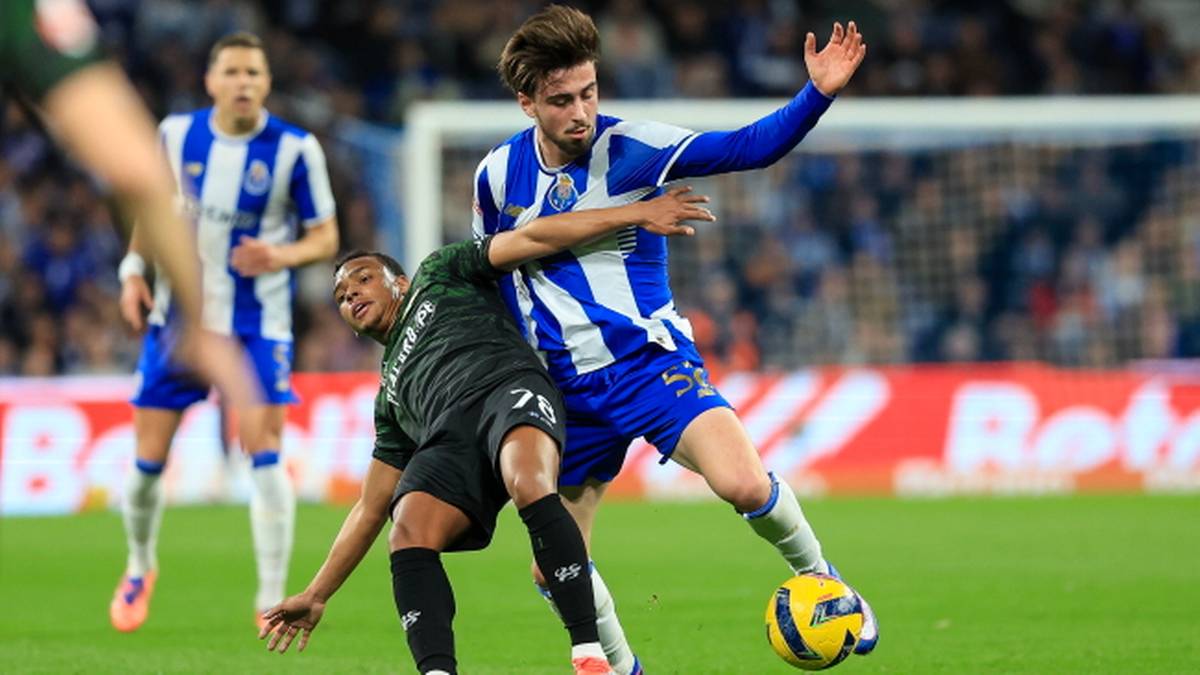 Piłkarz w niebiesko-białej koszulce FC Porto walczy o piłkę z zawodnikiem w czarnej koszulce.