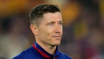 Dwóch piłkarzy w niebieskich bluzach, jeden z nich macha do publiczności.