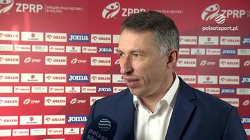 Sławomir Szmal, ubrany w granatową marynarkę i białą koszulę, mówi do mikrofonu z logo Polsatu.