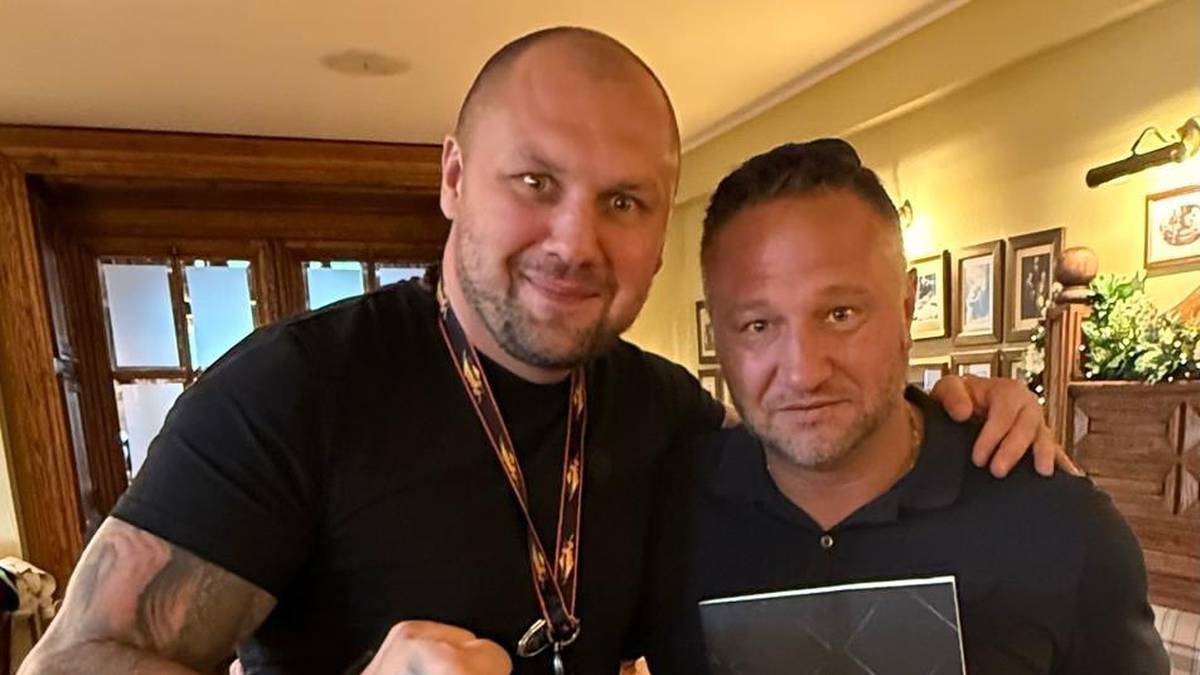 Dwóch mężczyzn pozuje do zdjęcia, jeden z nich zaciska pięść.