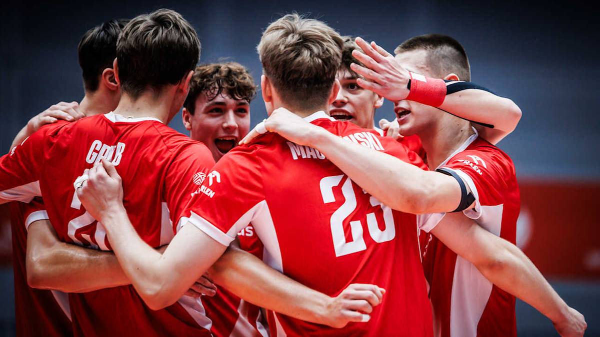 Drużyna siatkarzy w czerwonych koszulkach świętuje po meczu.