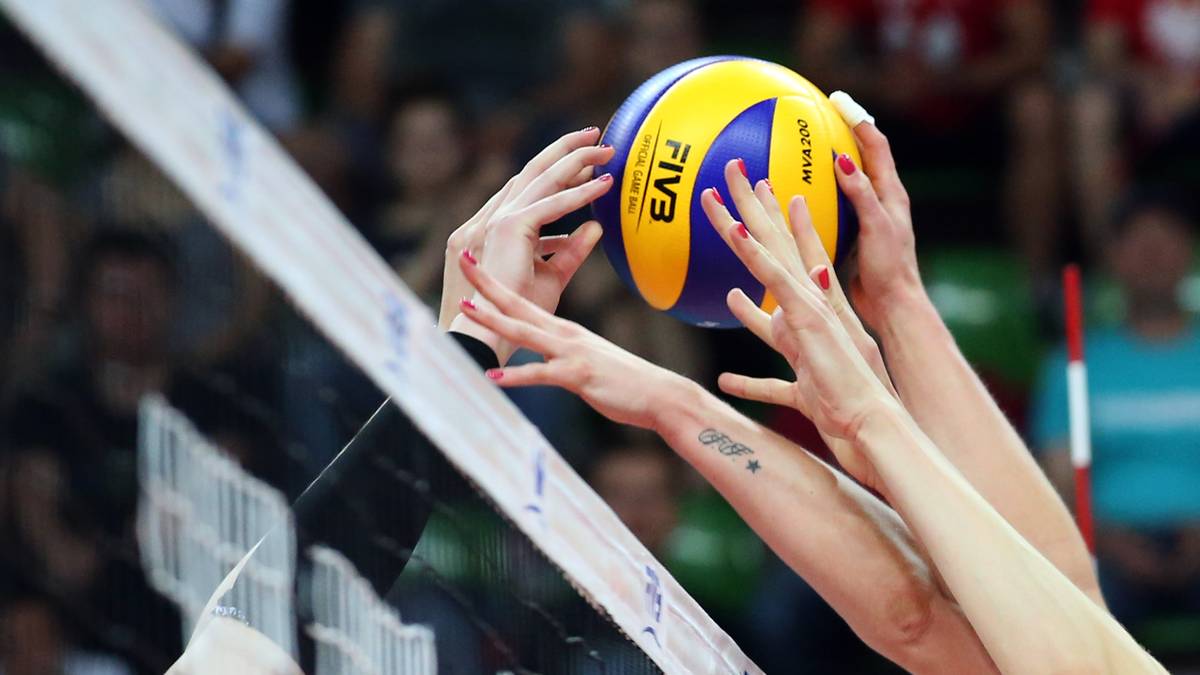 Dwie zawodniczki siatk&oacute;wki pr&oacute;bują zablokować piłkę nad siatką.