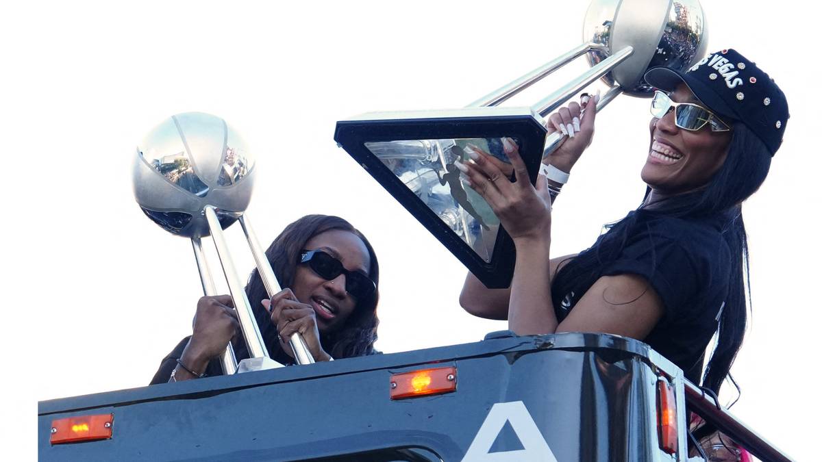 Dwie kobiety, jedna z nich uśmiecha się, trzymają trofea na tle białego nieba.