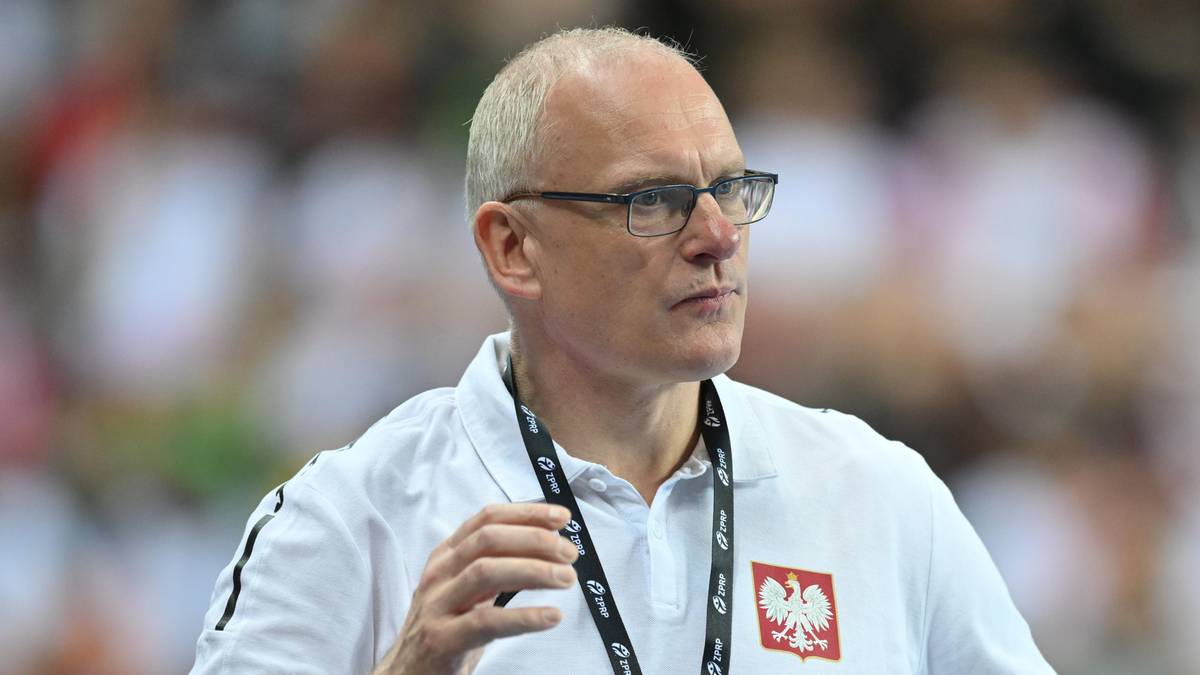 Mężczyzna w okularach, ubrany w białą koszulkę z polskim godłem, jest trenerem reprezentacji Polski.