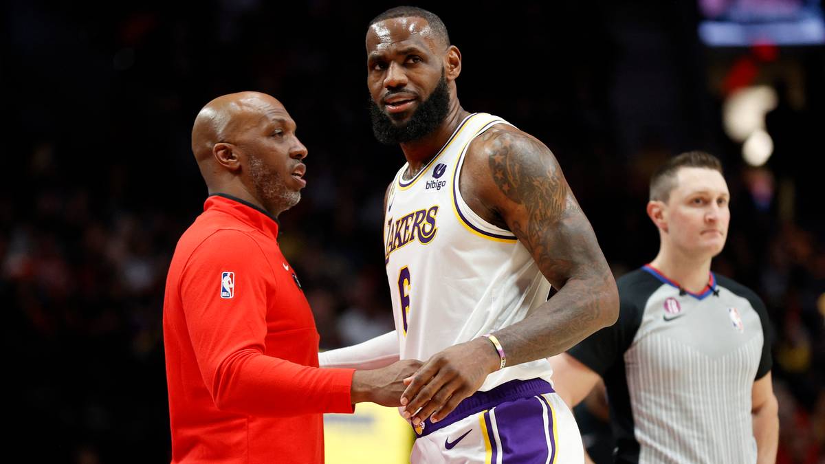 LeBron James w stroju Los Angeles Lakers rozmawia z trenerem w czerwonej bluzie. W tle widać sędziego.