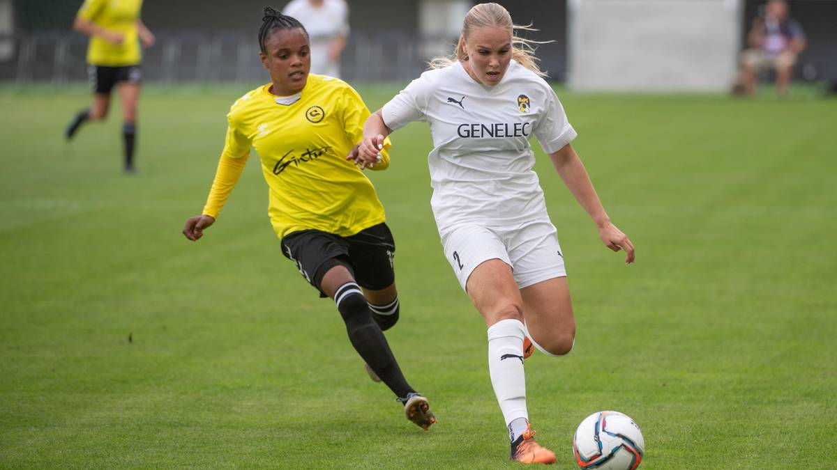 Dwie piłkarki zmagają się o piłkę na zielonej murawie stadionu.