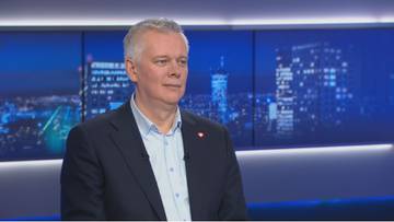 Mężczyzna w średnim wieku w garniturze przed ekranem z nocnym miastem.