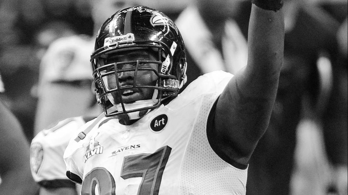 Gracz futbolu amerykańskiego w hełmie i stroju z numerem 97 unosi rękę w geście zwycięstwa.