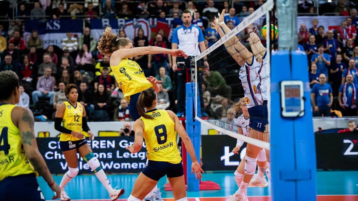 Zawodniczka w ż&oacute;łtym stroju odbija piłkę nad siatką podczas meczu siatk&oacute;wki, po drugiej stronie siatki znajduje się przeciwniczka.