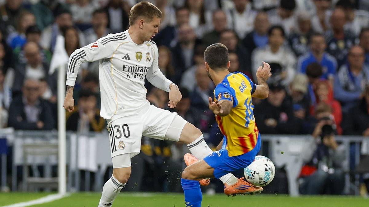 Piłkarz Realu Madryt w białej koszulce z numerem 30 próbuje odebrać piłkę przeciwnikowi.