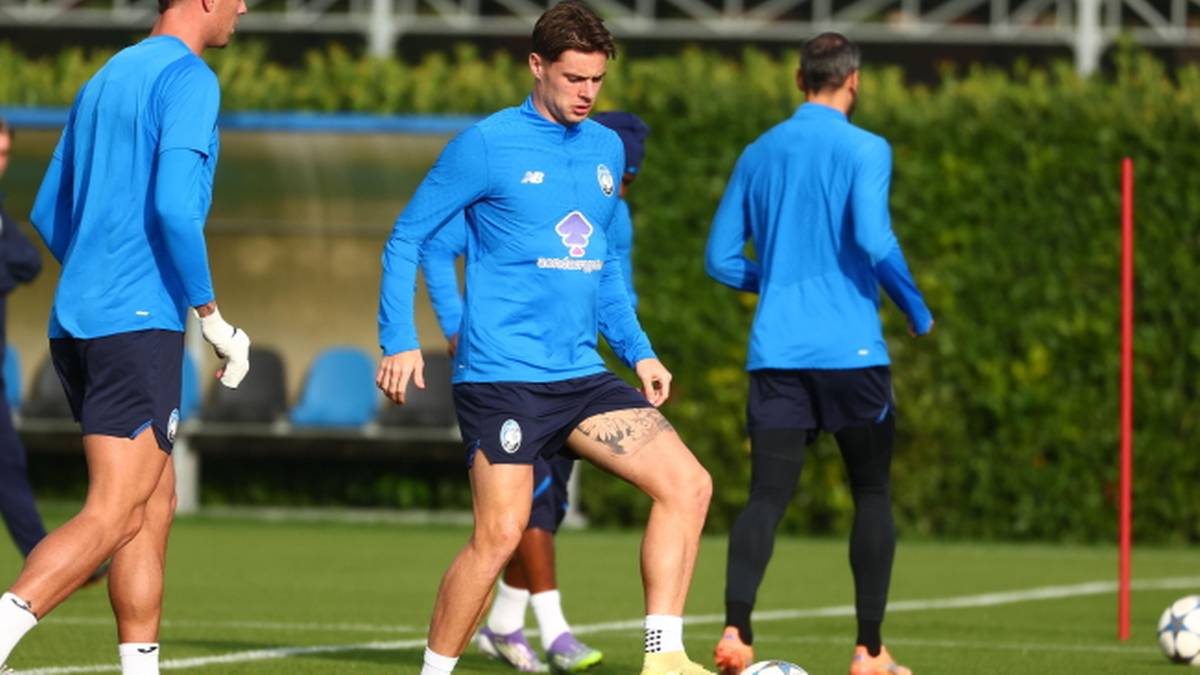 Trzech piłkarzy w niebieskich strojach na boisku treningowym.