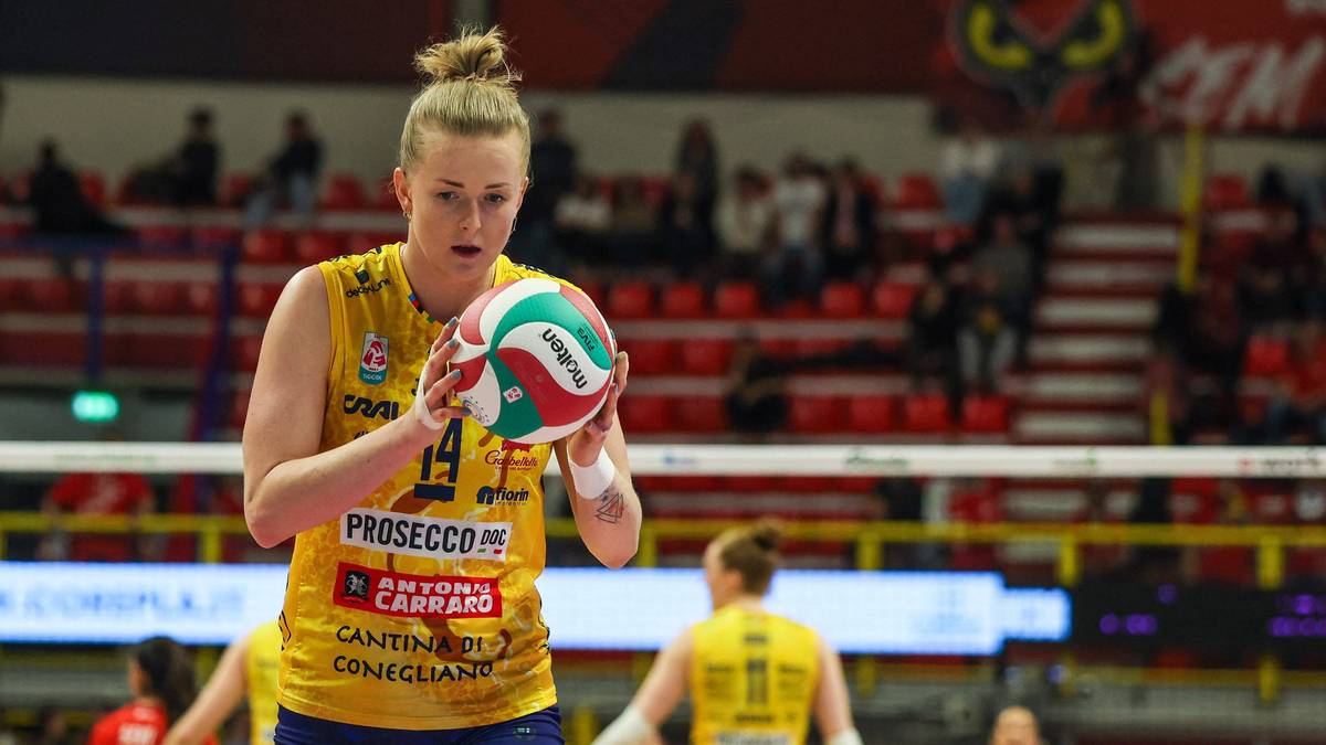 Siatkarka w ż&oacute;łtej koszulce z numerem 14 trzyma piłkę do siatk&oacute;wki, gotowa do gry.