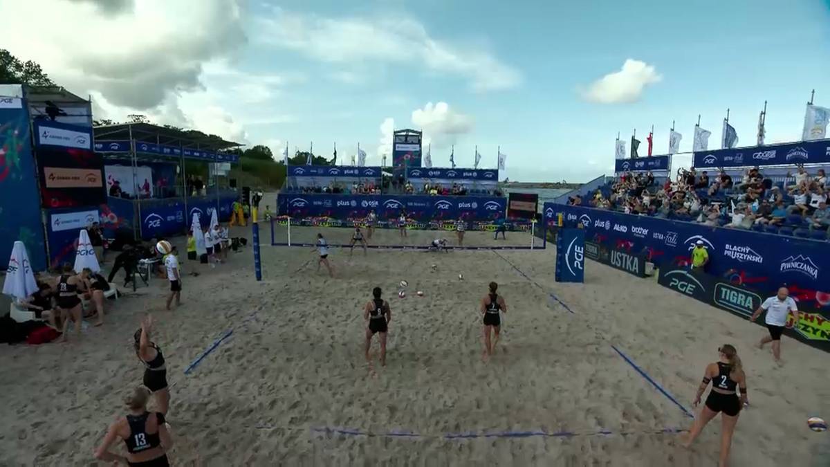 Boisko do siatkówki plażowej z zawodnikami i publicznością.