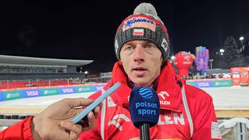 Dawid Kubacki w czerwonej kurtce i zimowej czapce udziela wywiadu z mikrofonem Polsat Sport.