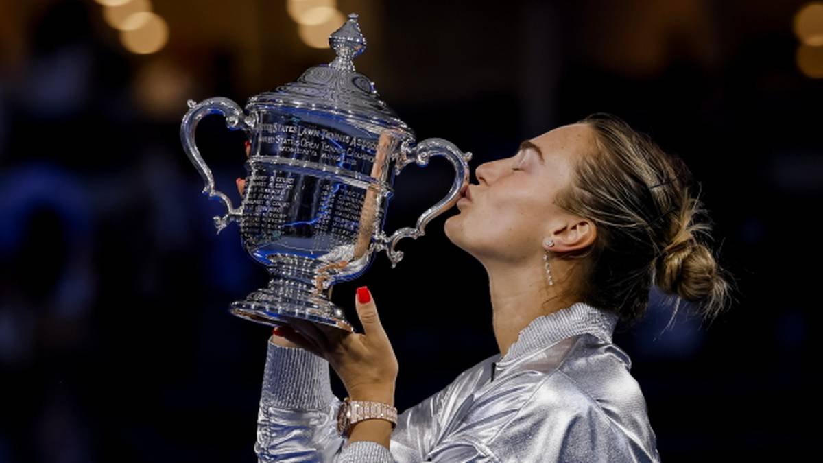 Tenisistka Aryna Sabalenka całuje srebrne trofeum, trzymając je obiema rękami.
