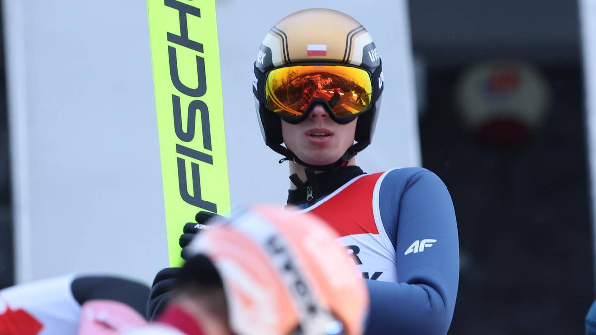 Skoczek narciarski w kasku i goglach z nartą