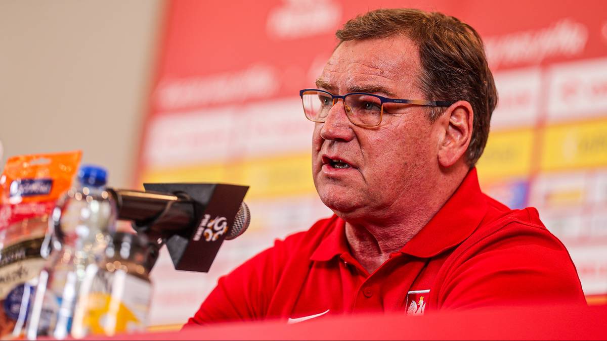 Trener Jan Urban przemawiający do mikrofonu podczas konferencji prasowej.