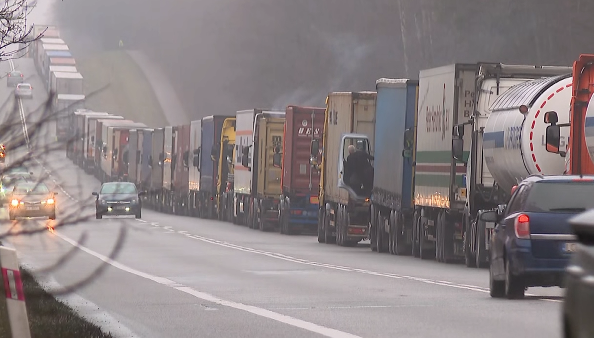 Długa kolejka ciężar&oacute;wek stojących na drodze.