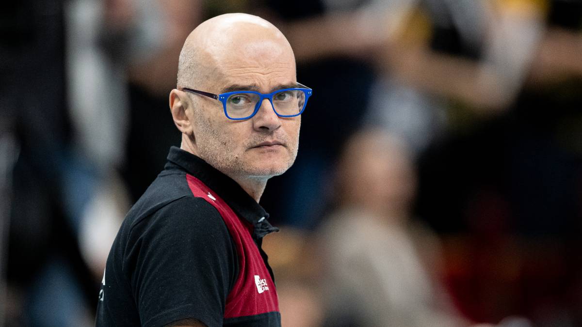 Portret łysego mężczyzny w okularach, prawdopodobnie trenera siatk&oacute;wki, patrzącego w obiektyw z zamyślonym wyrazem twarzy.